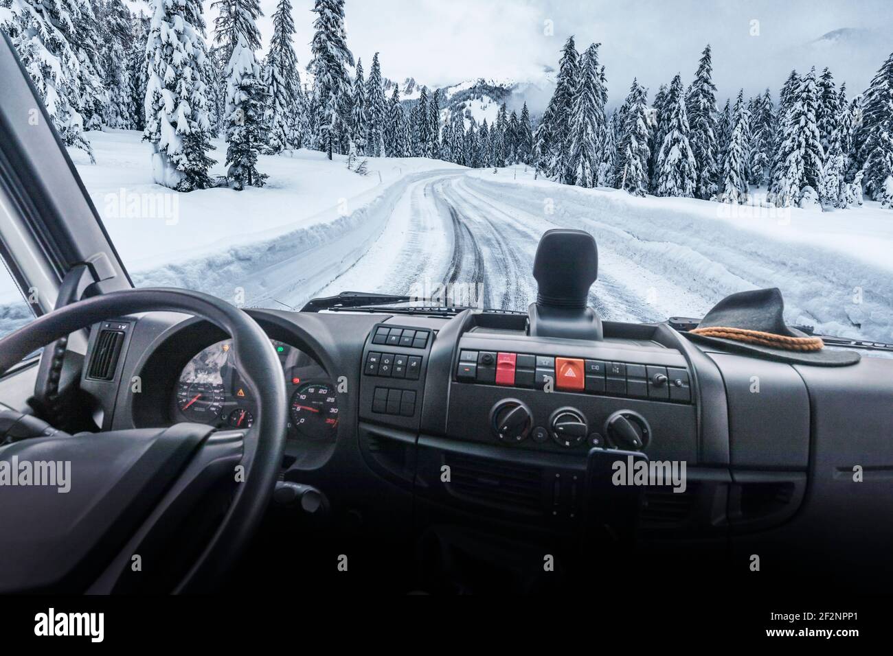 snowy mountain road seen from the cab of a truck, commercial vehicle. Dolomites, Belluno, Veneto, Italy Stock Photo