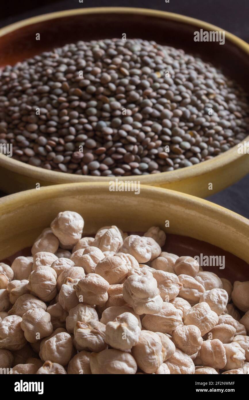 Close-up of a pile of white chickpeas on crockery and lentils out of focus in the background. Legumes and raw foods. Stock Photo
