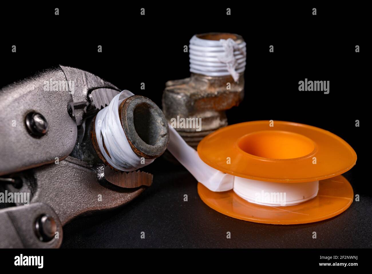 Plumbing fittings and accessories. Pipe connections with Teflon tape. Dark background. Stock Photo