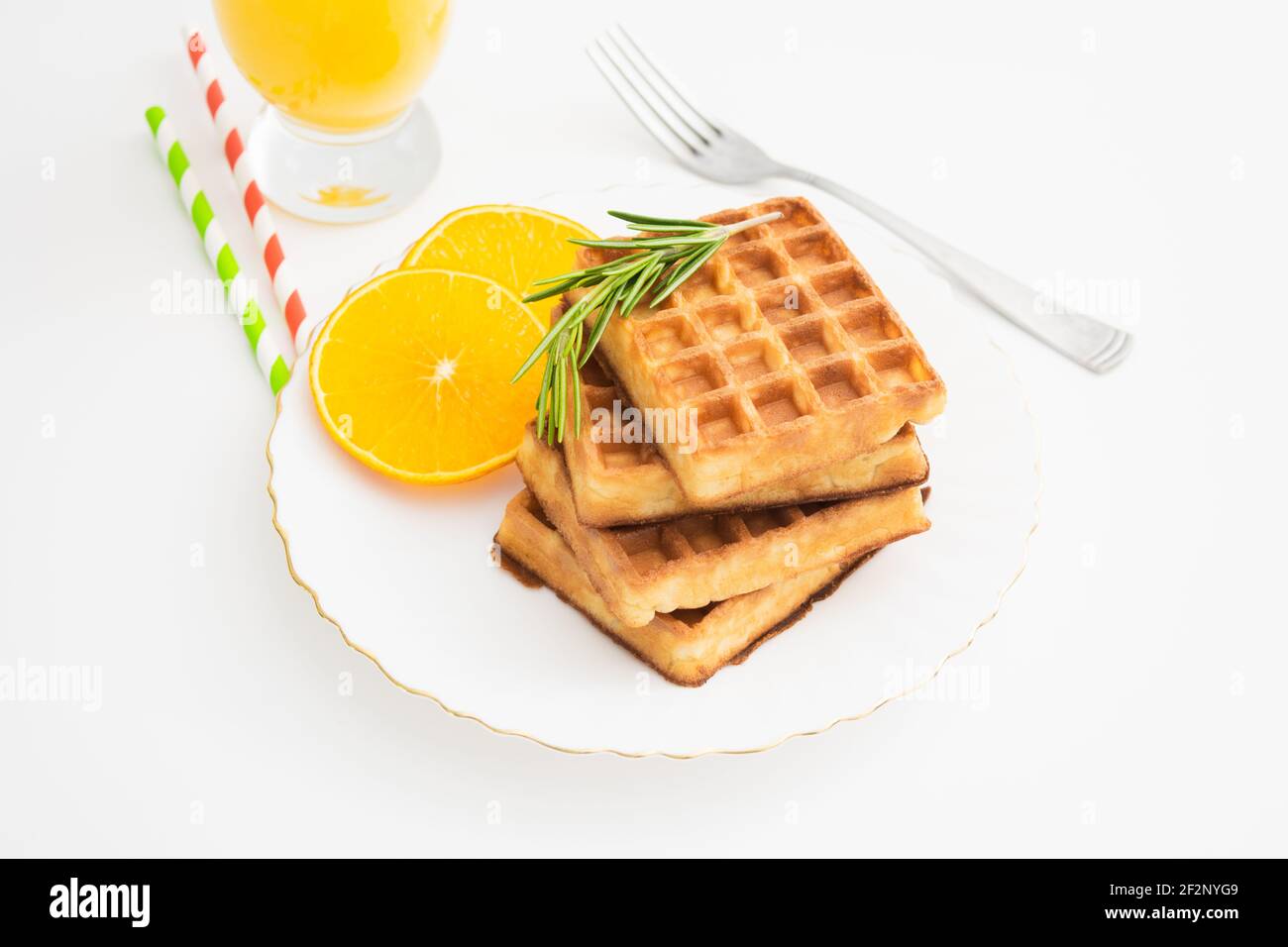 Breakfast with belgium waffles with rosemary and orange slices. Closeup view Stock Photo