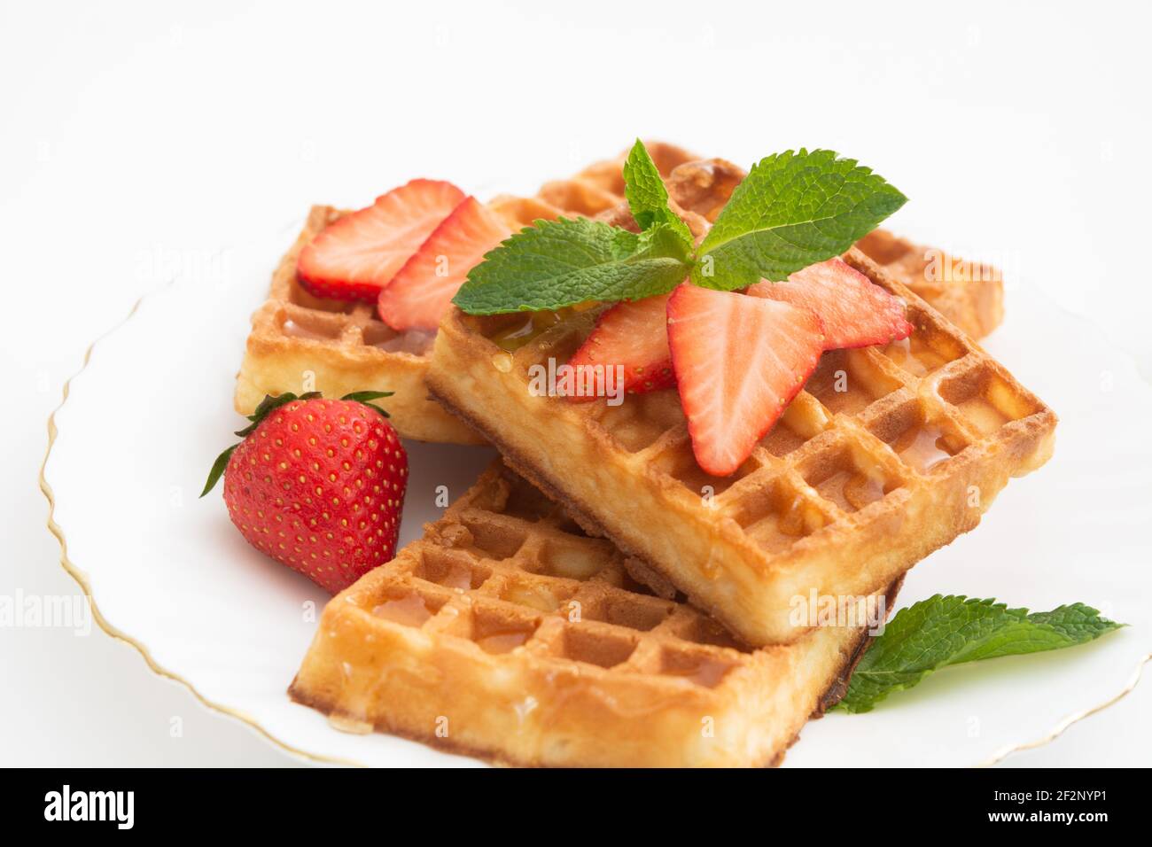 Breakfast with belgium waffles with strawberry, mint on plate and orange juice Stock Photo