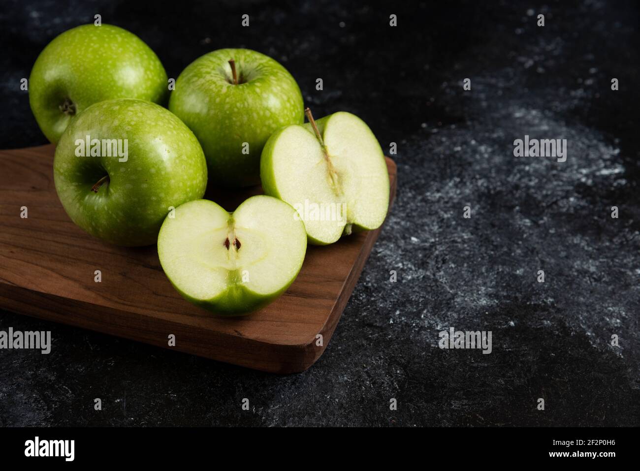 Whole and sliced ripe green apples on wooden board Stock Photo