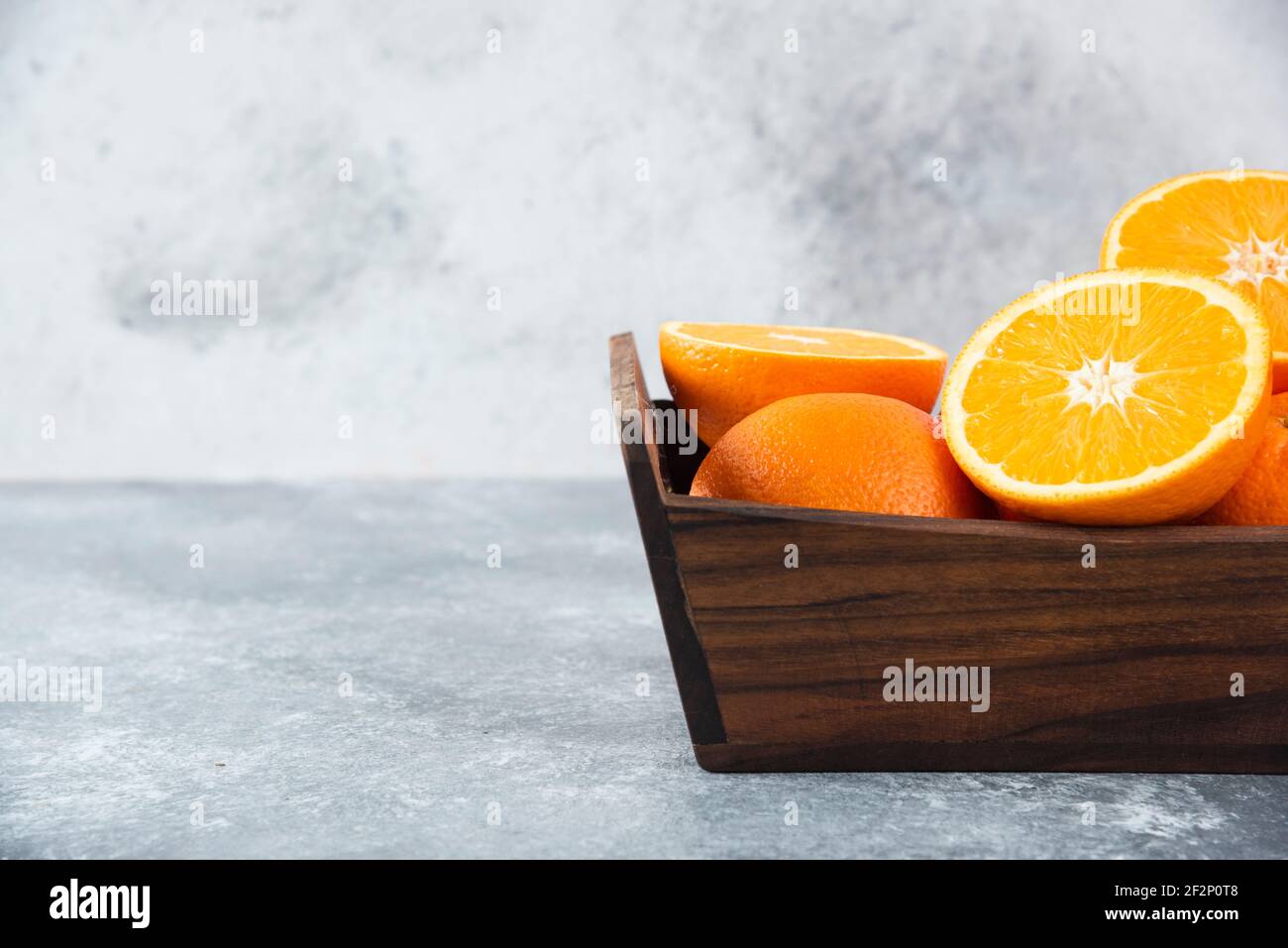 A wooden old box full of sliced and whole juicy orange fruits Stock Photo