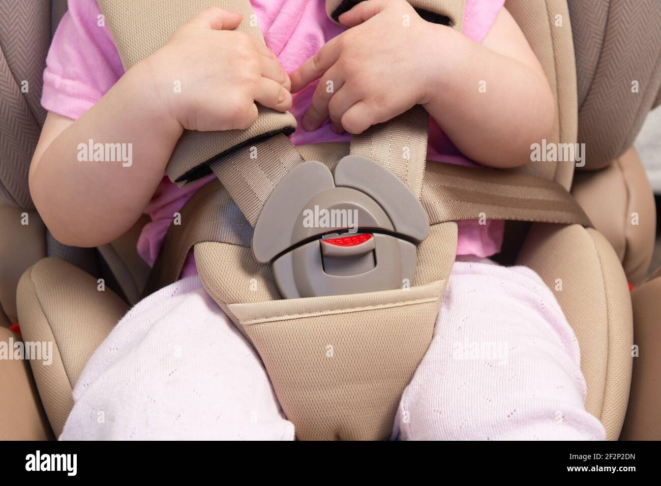 Faceless small baby sitting in special car seat with safety seatbelts Stock Photo