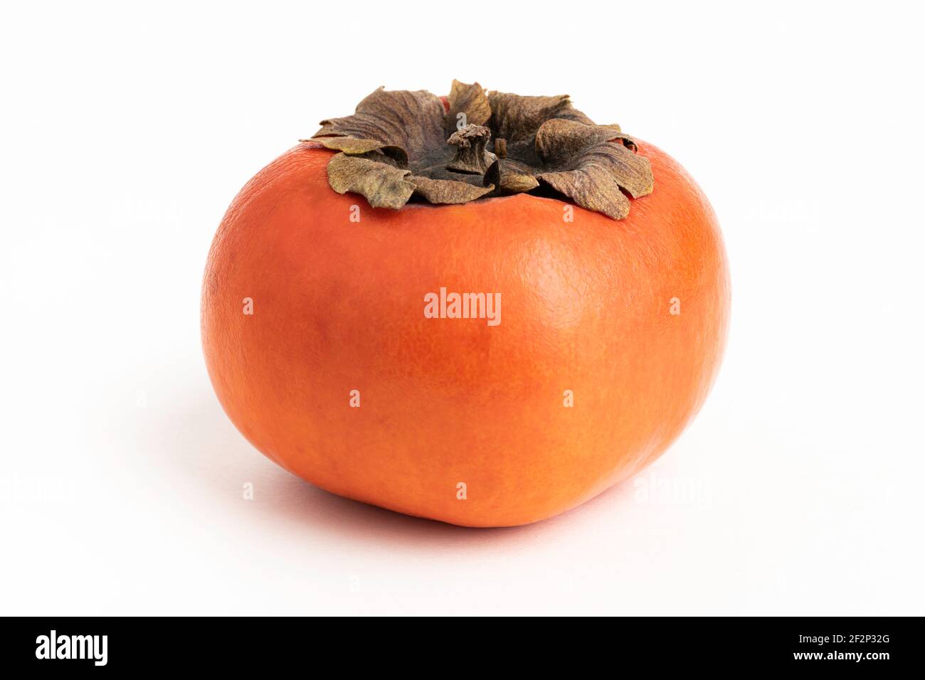 Close-up shot with shallow depth of field of a ripe persimmon fruit set on a plain white background. Stock Photo