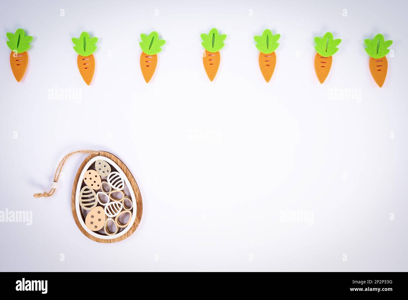 Easter pattern made with carrots and a cute Easter egg decoration on white background. Creative minimal holiday flat lay concept. Spring holidays. Stock Photo