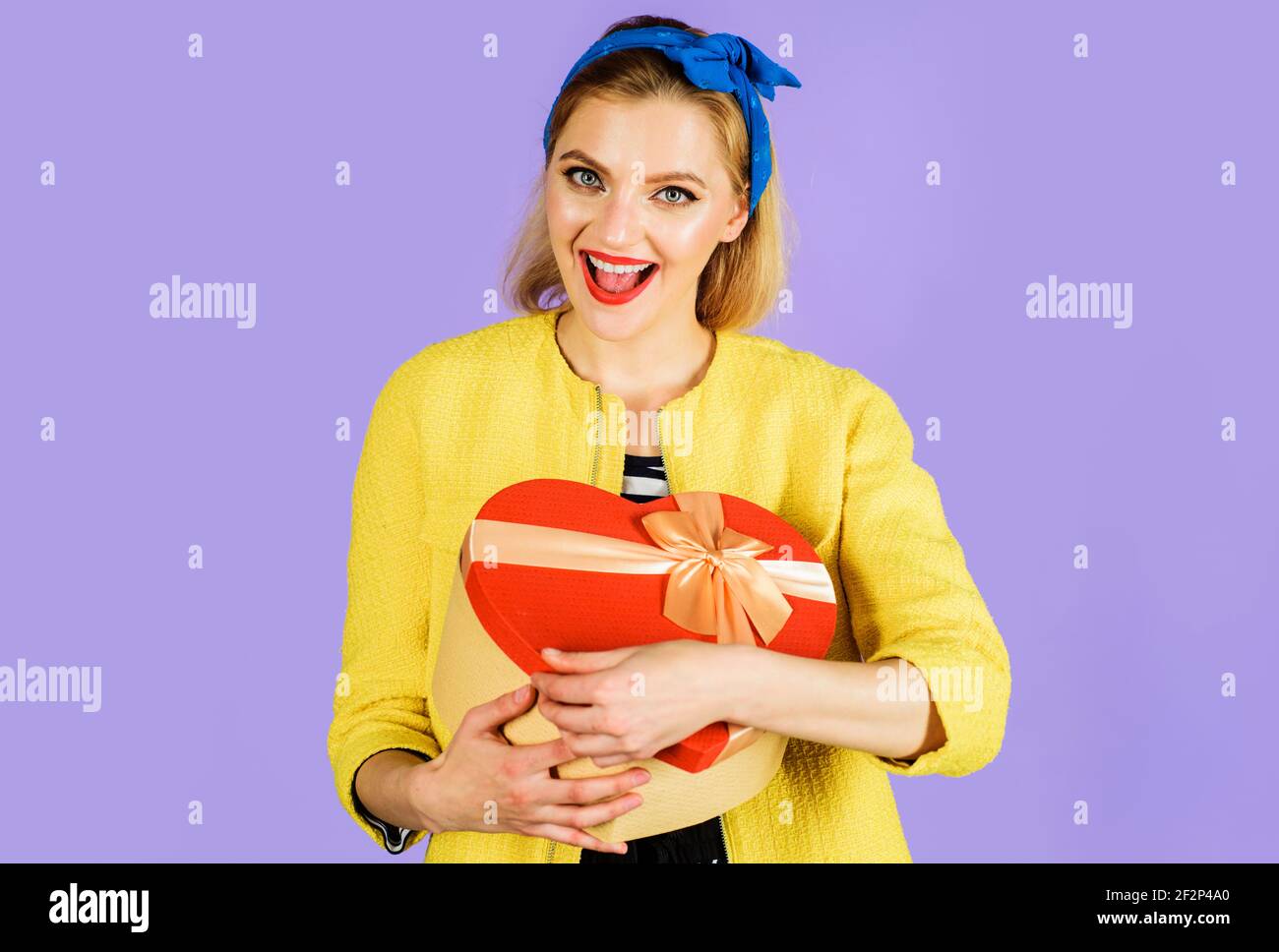 Smiling Woman with red heart gift. Present with love. Womans Day, Mothers Day, Birthday concept. Stock Photo