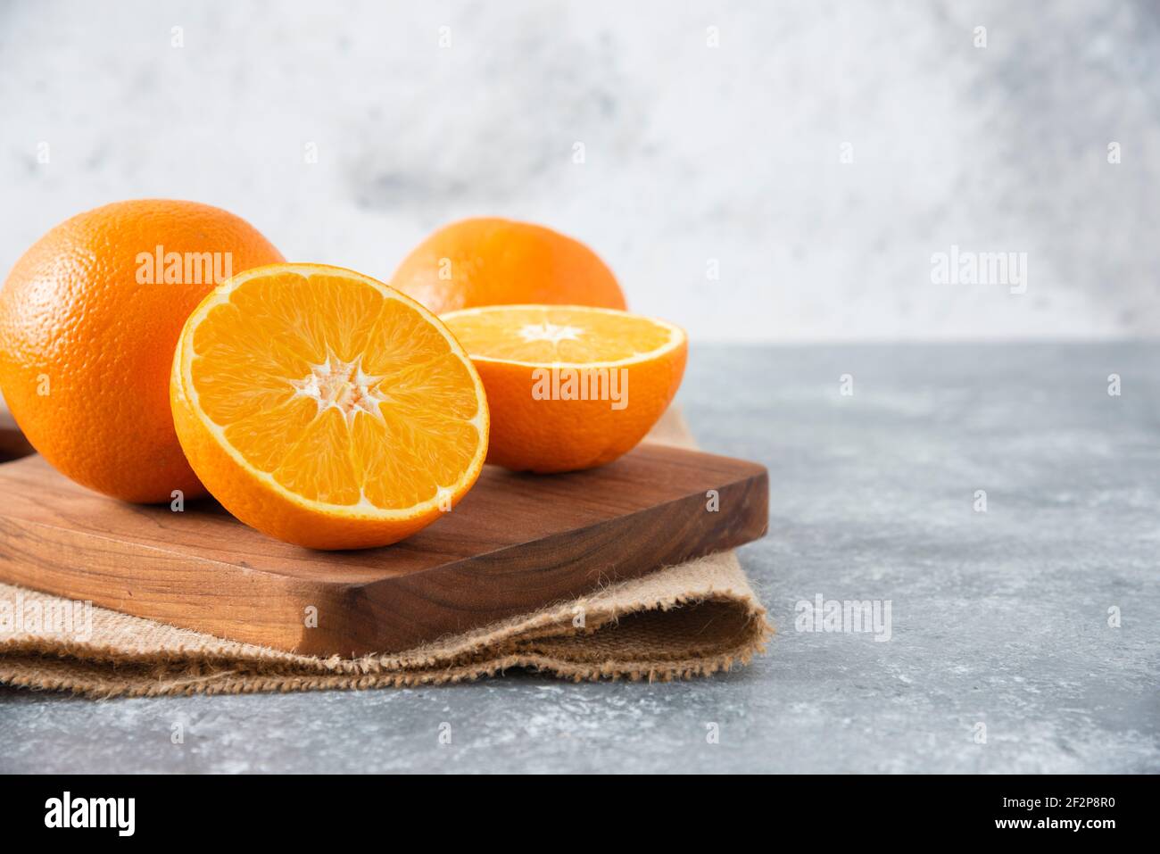 A wooden board full of juicy slices of orange fruit on stone background Stock Photo
