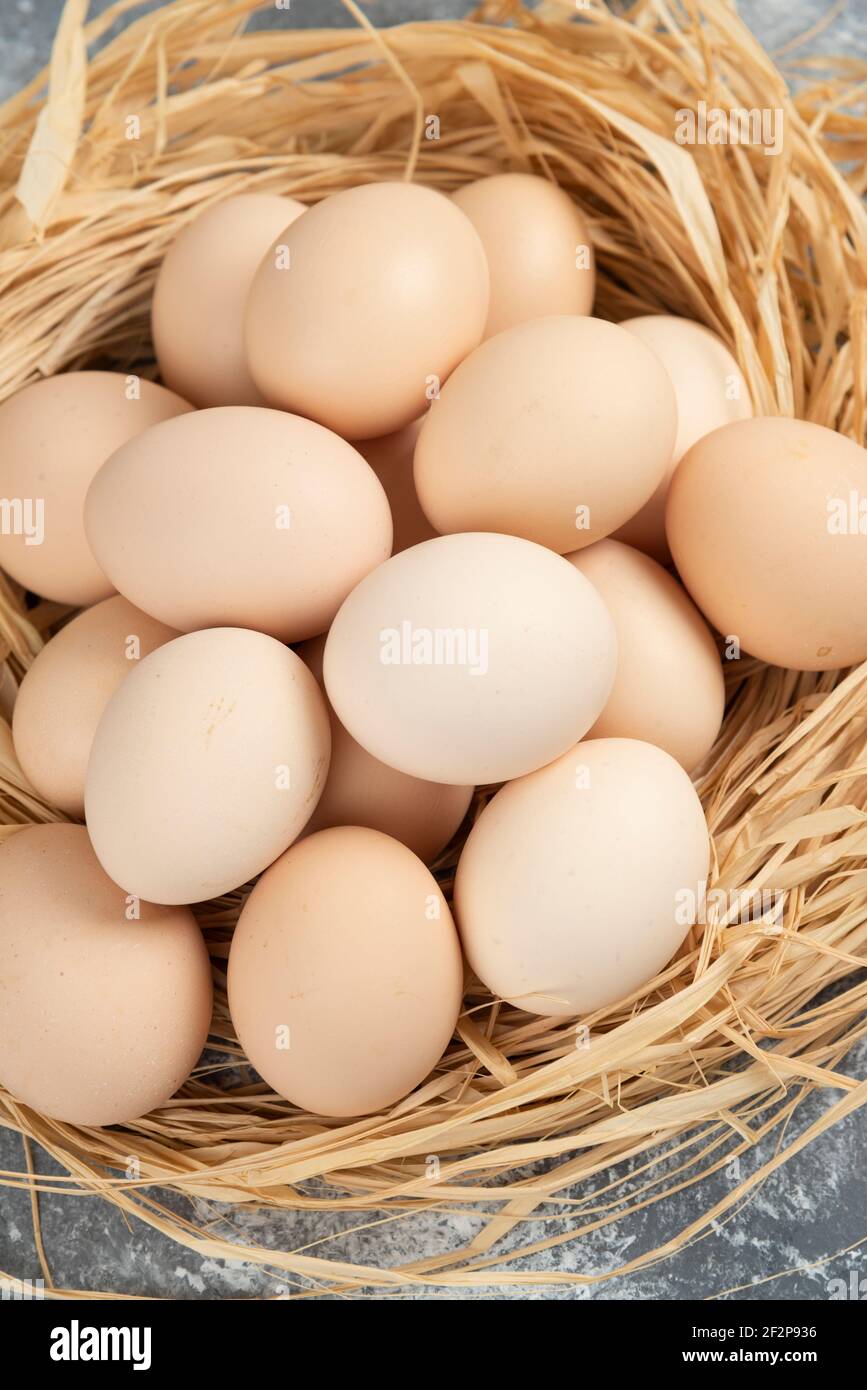Bunch of raw eggs with bird nest on marble surface Stock Photo