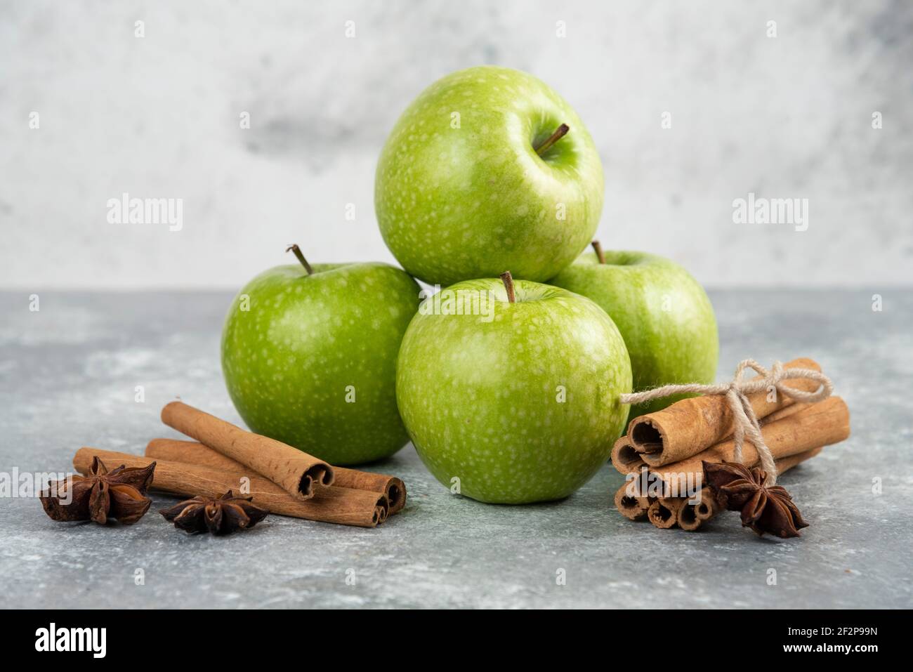 Whole green apples and cinnamon sticks on marble background Stock Photo