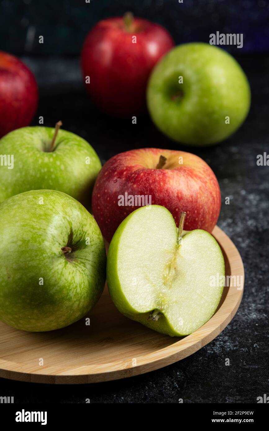 Whole and sliced green and red apples on wooden plate Stock Photo