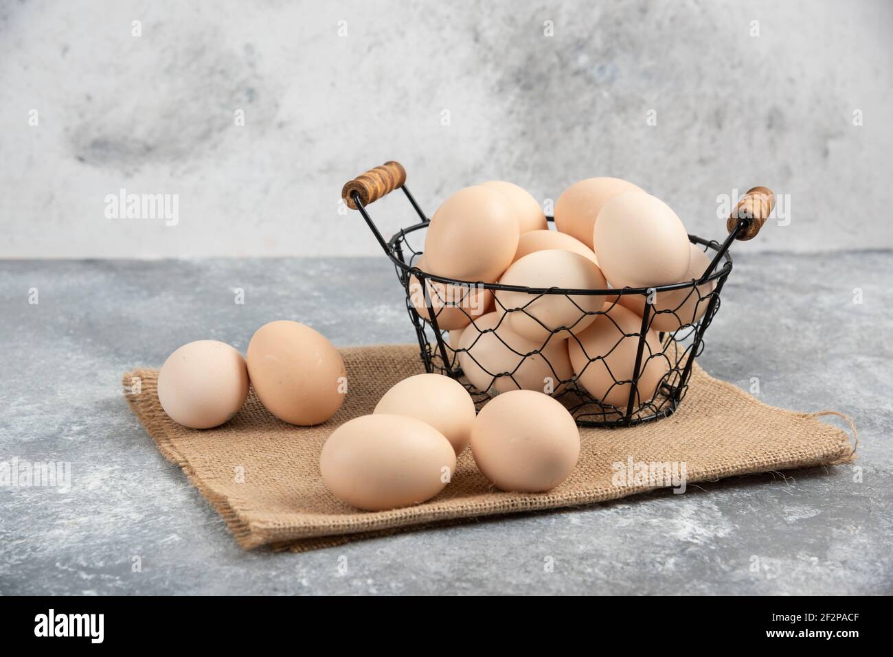 Wicker basket of raw organic eggs on marble background Stock Photo
