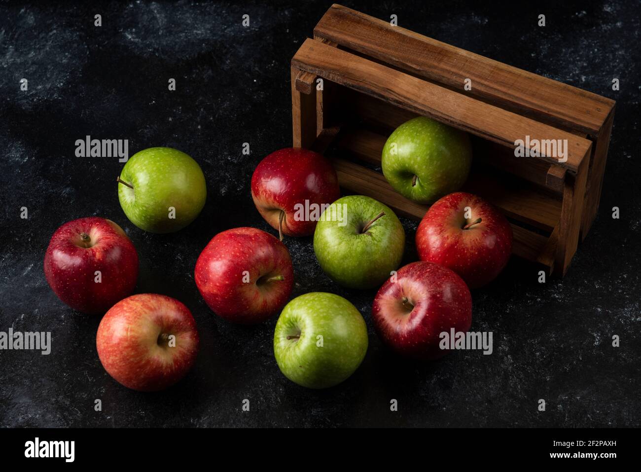 Ripe organic apples out of wooden box on black background Stock Photo