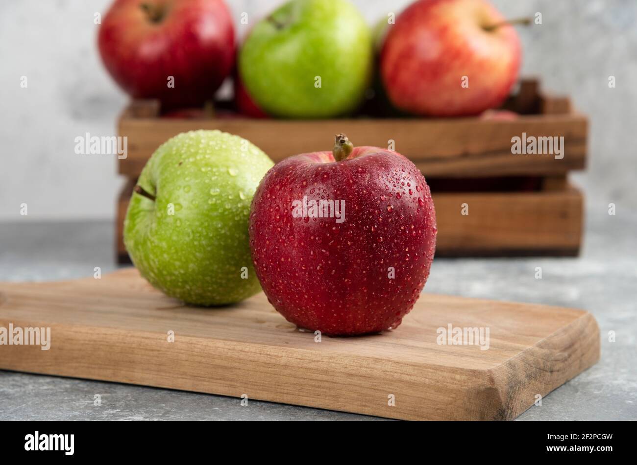Whole wet green and red apples on wooden cutting board Stock Photo