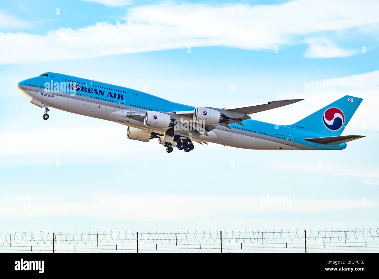 London, UK, Jun 2019 - Korean Air Boeing 747 Jumbo Jet taking off alongside the Airport Perimeter fence with its landing carriage still completely dow Stock Photo