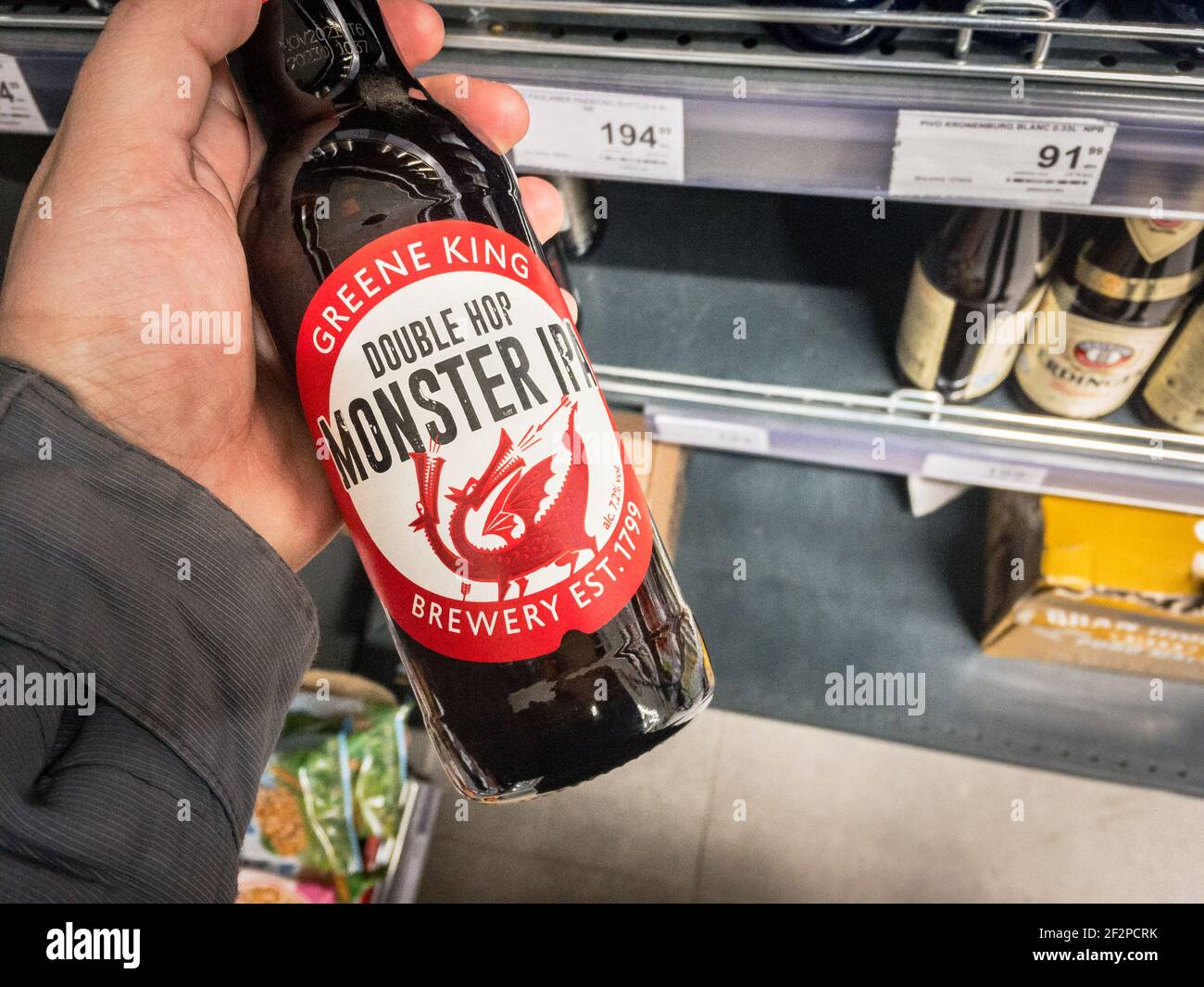BELGRADE, SERBIA - MARCH 2 2021: Hands holding a bottle of Greene King Douple Hop Monster IPA beer. Greene King is a British chain of pubs and brewery Stock Photo