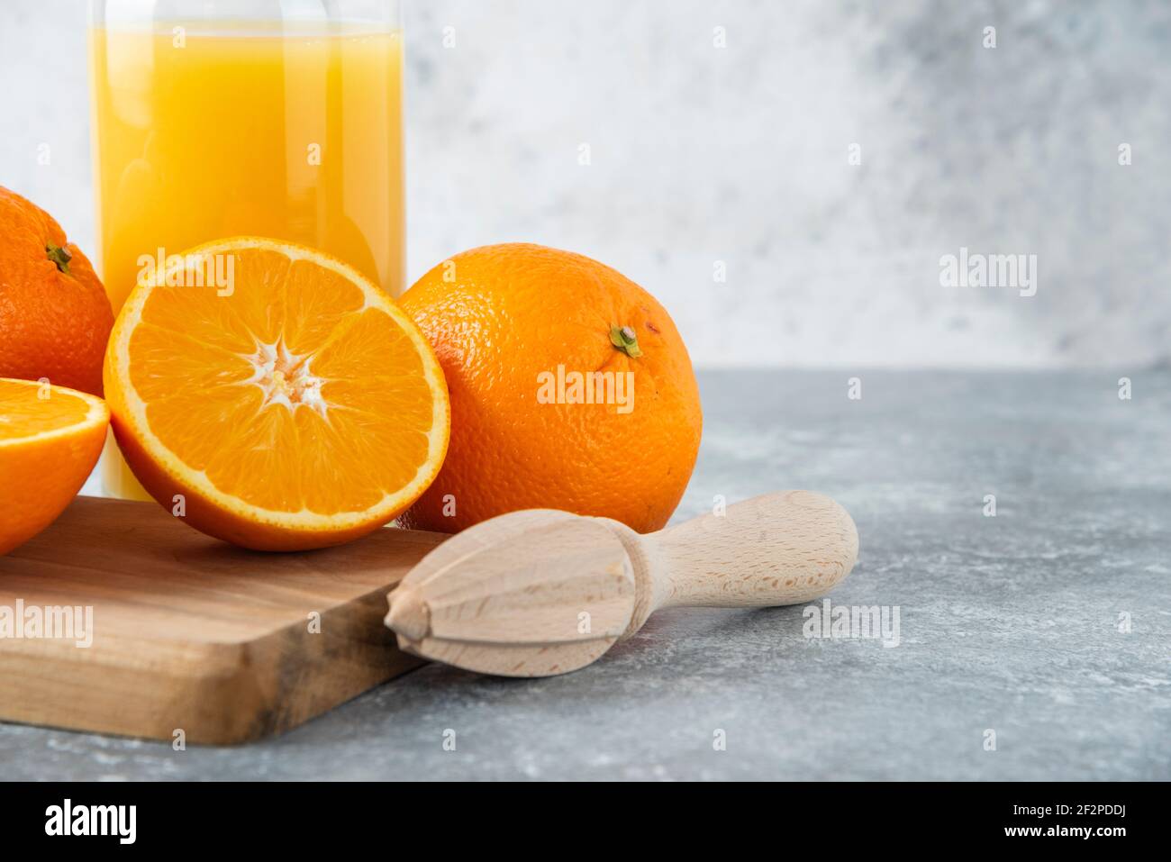 Glass pitcher of juice with sliced orange fruit on a wooden board Stock Photo