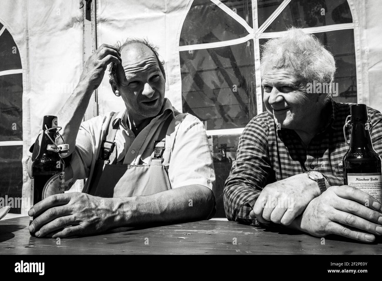 Germany, Bavaria, Antdorf, festival week of the traditional costume association. Two men take a break while setting up the marquee and drink beer. Stock Photo