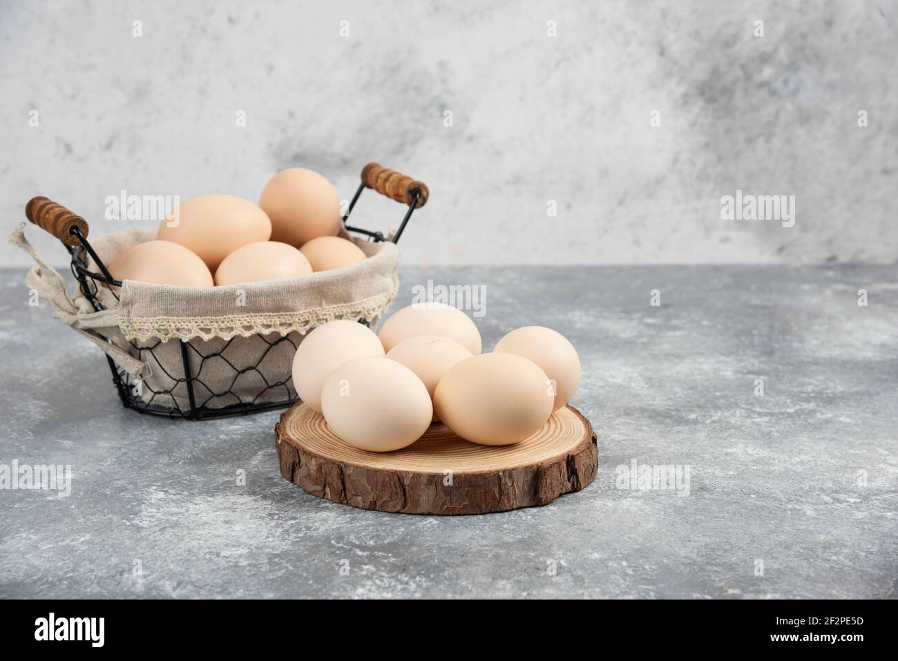 Basket of organic fresh uncooked eggs placed on marble surface Stock Photo