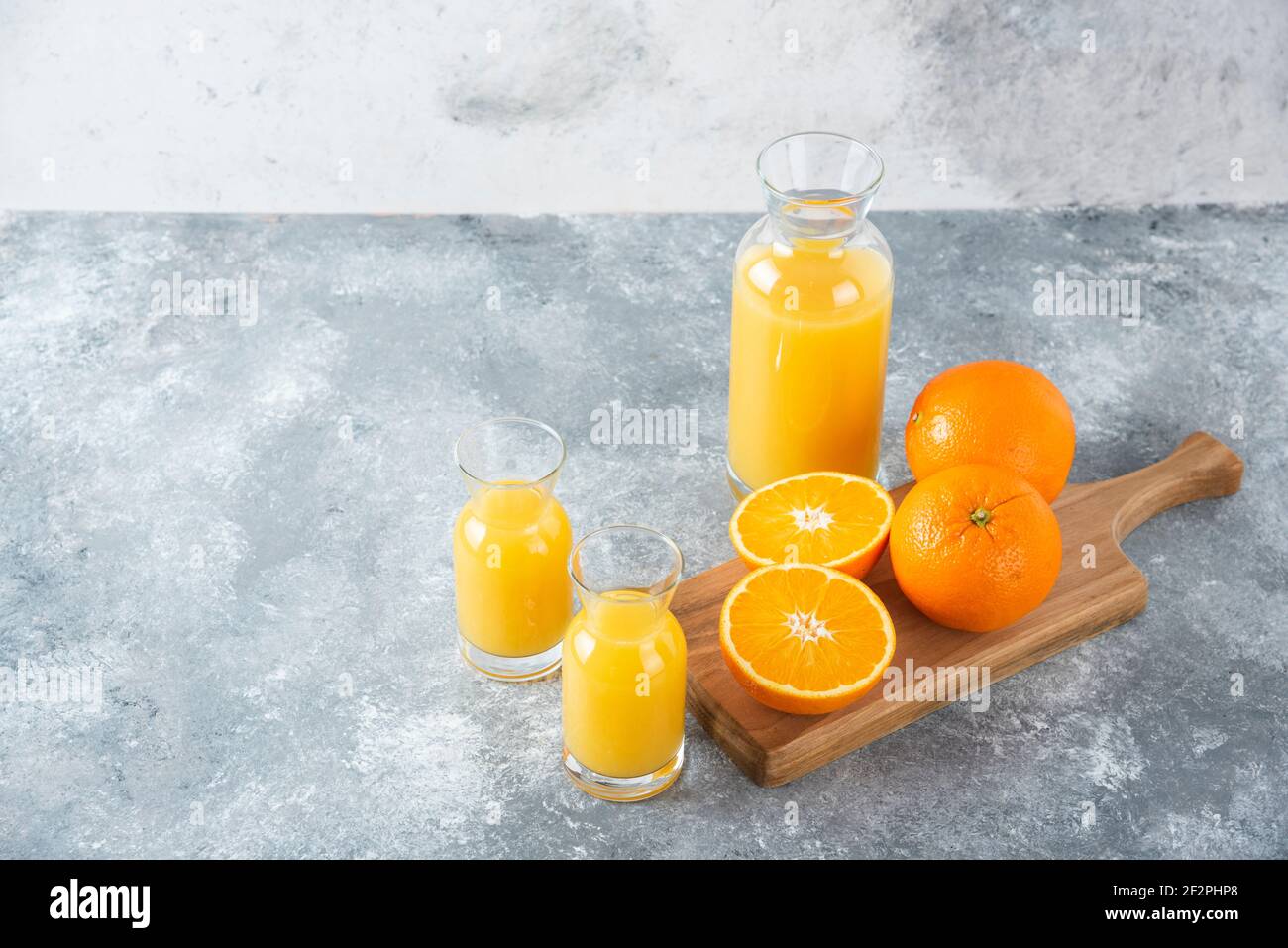 Glass pitcher of juice with sliced orange fruit on a wooden board Stock Photo
