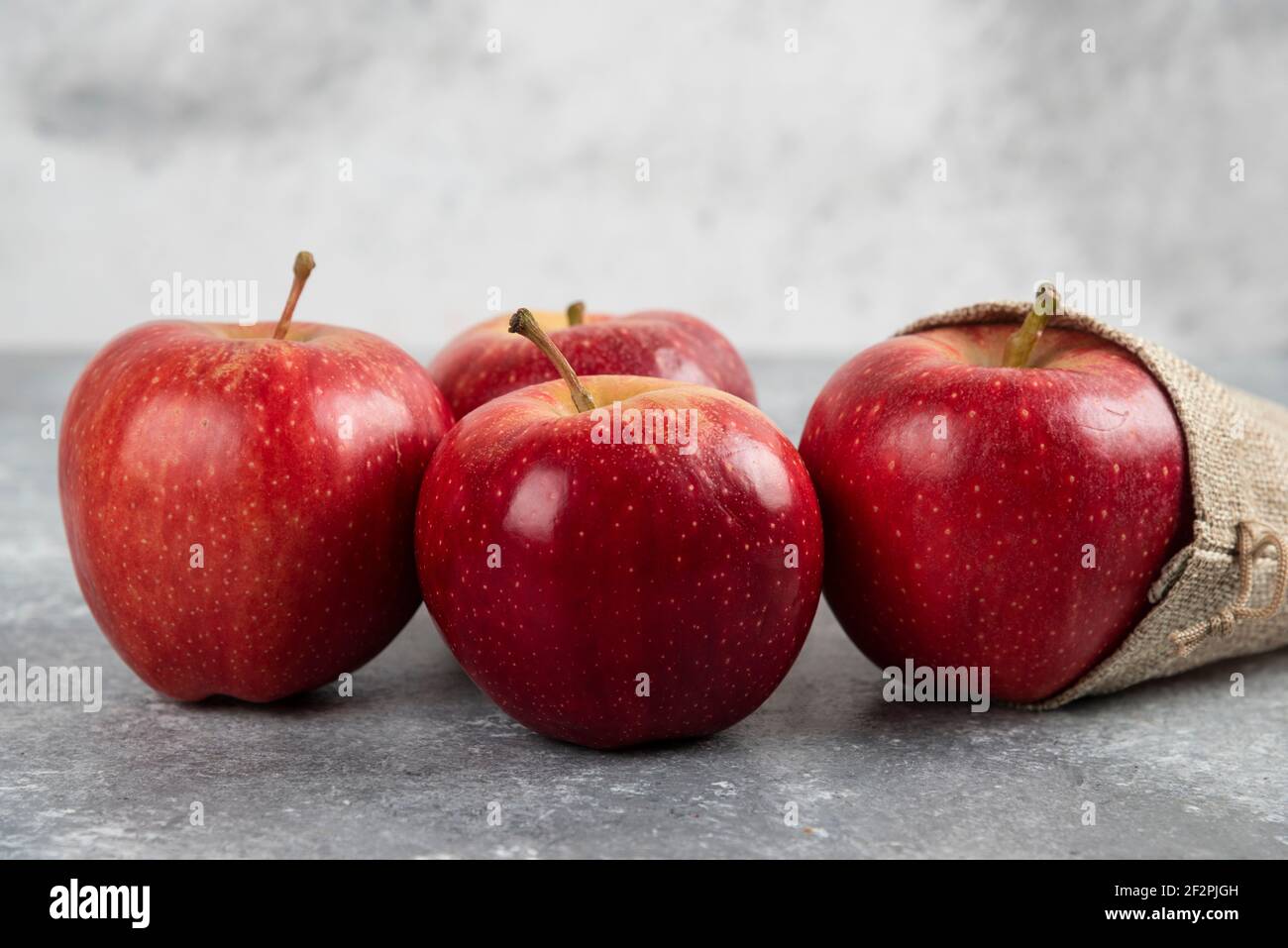 Delicious red apples out of burlap on marble background Stock Photo