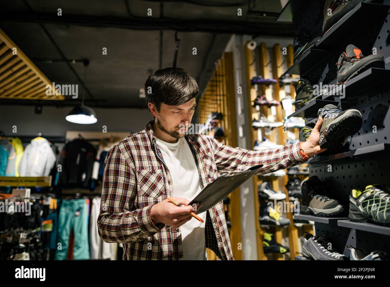 Sporting goods store owner with clipboard checking inventory. Tourist store  manager working near showcase with hiking boots makes check list of orders  Stock Photo - Alamy