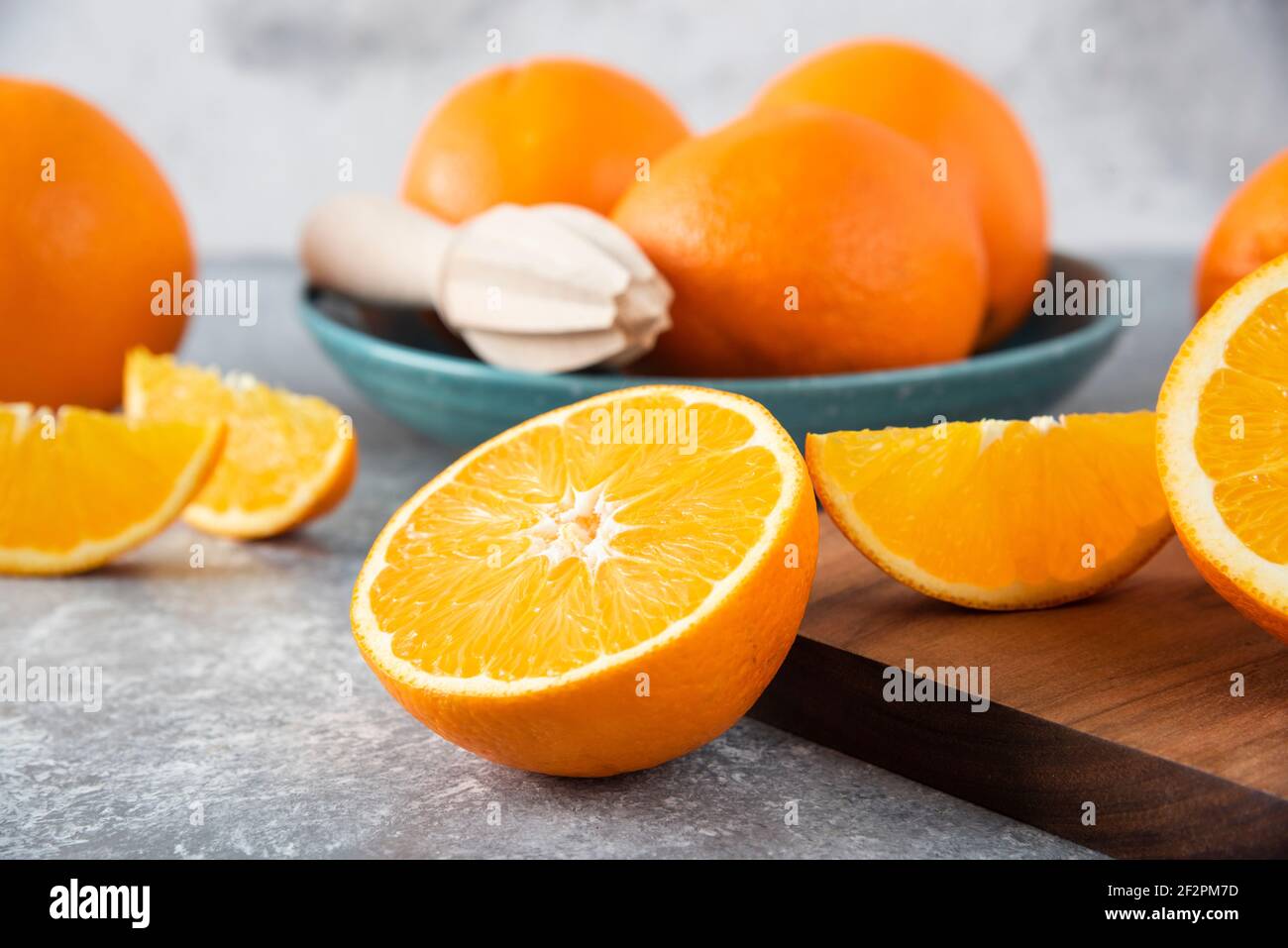Sliced orange fruits with whole oranges on a wooden board Stock Photo