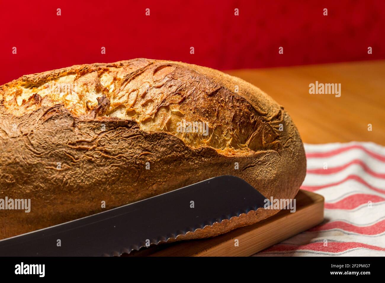 Fresh homemade organic bread with bread knife on wooden plate Stock Photo