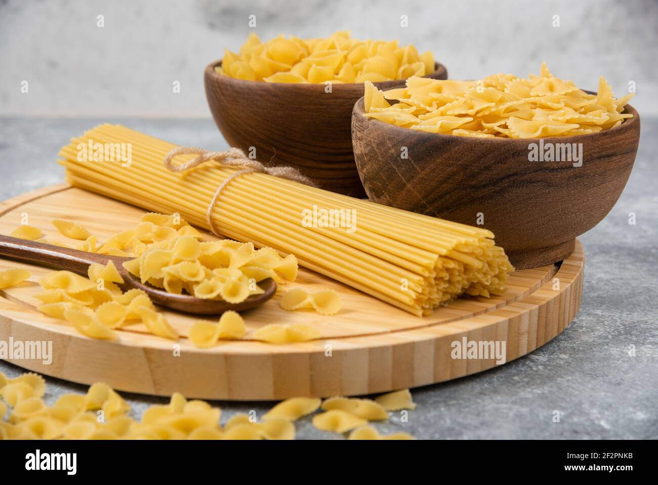 Bowls of raw dry pasta and spaghetti on marble surface Stock Photo