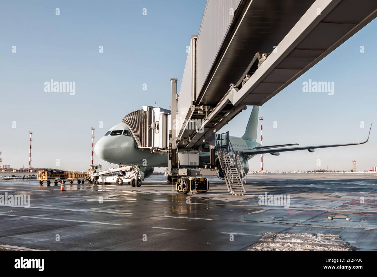 The passenger jet plane stands at the air bridge on an airport apron. The baggage is being loaded Stock Photo