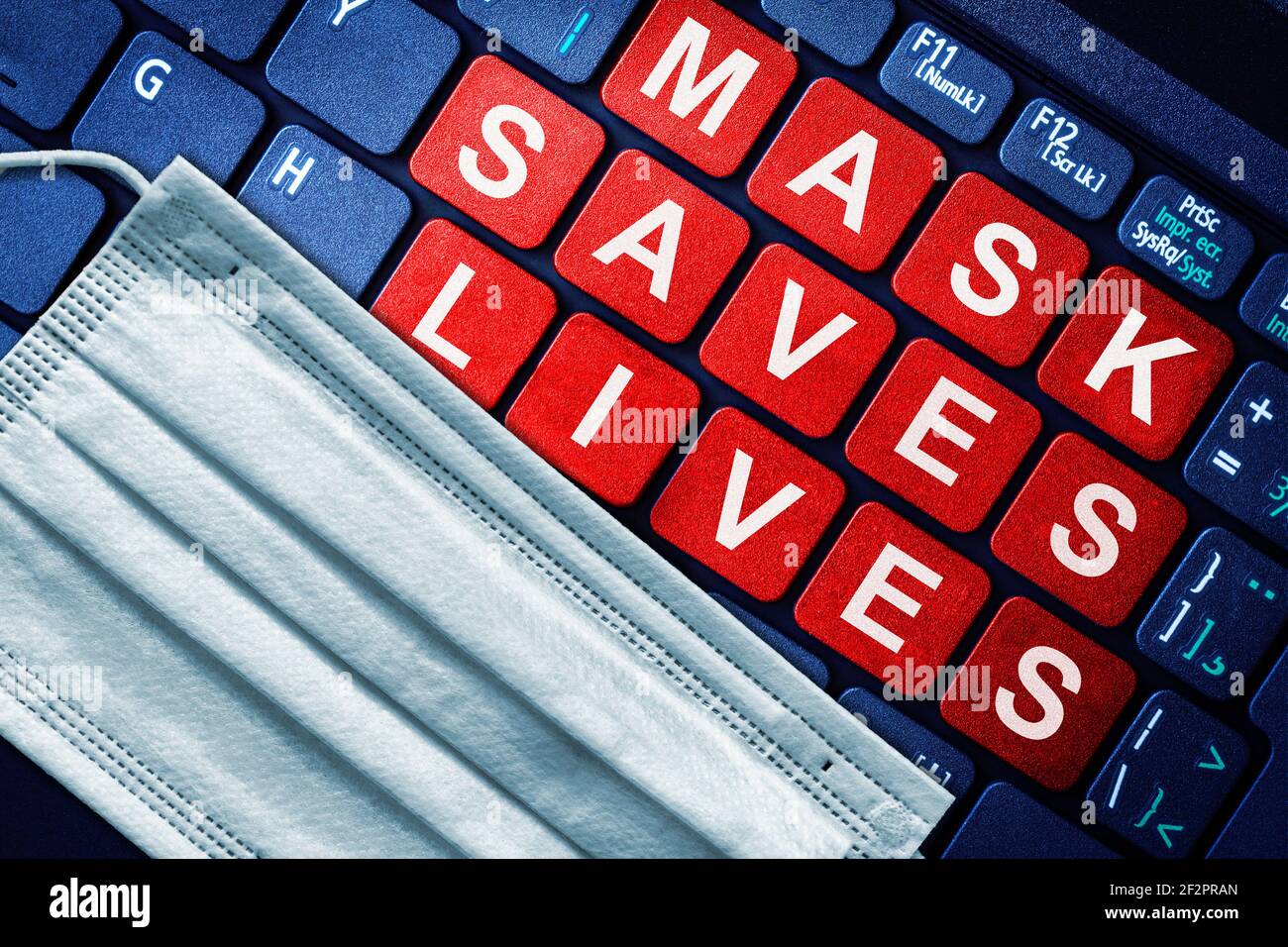 Wearing face mask saves lives concept in the new normal during COVID-19 pandemic outbreak, shown with medical mask on keyboard with red keys highlight Stock Photo