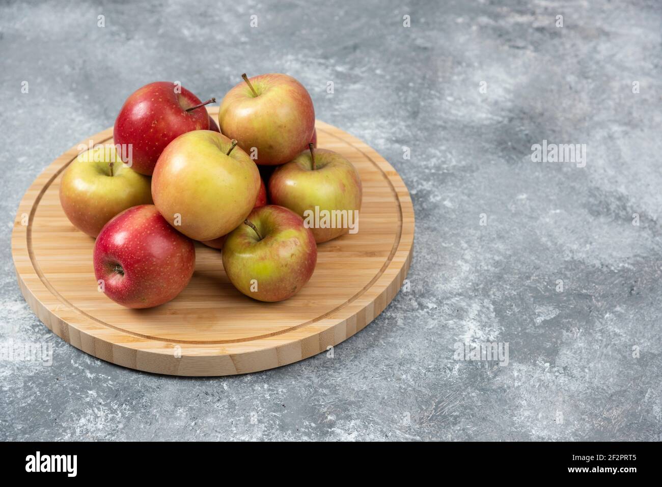 Bunch of fresh ripe apples placed on wooden board Stock Photo