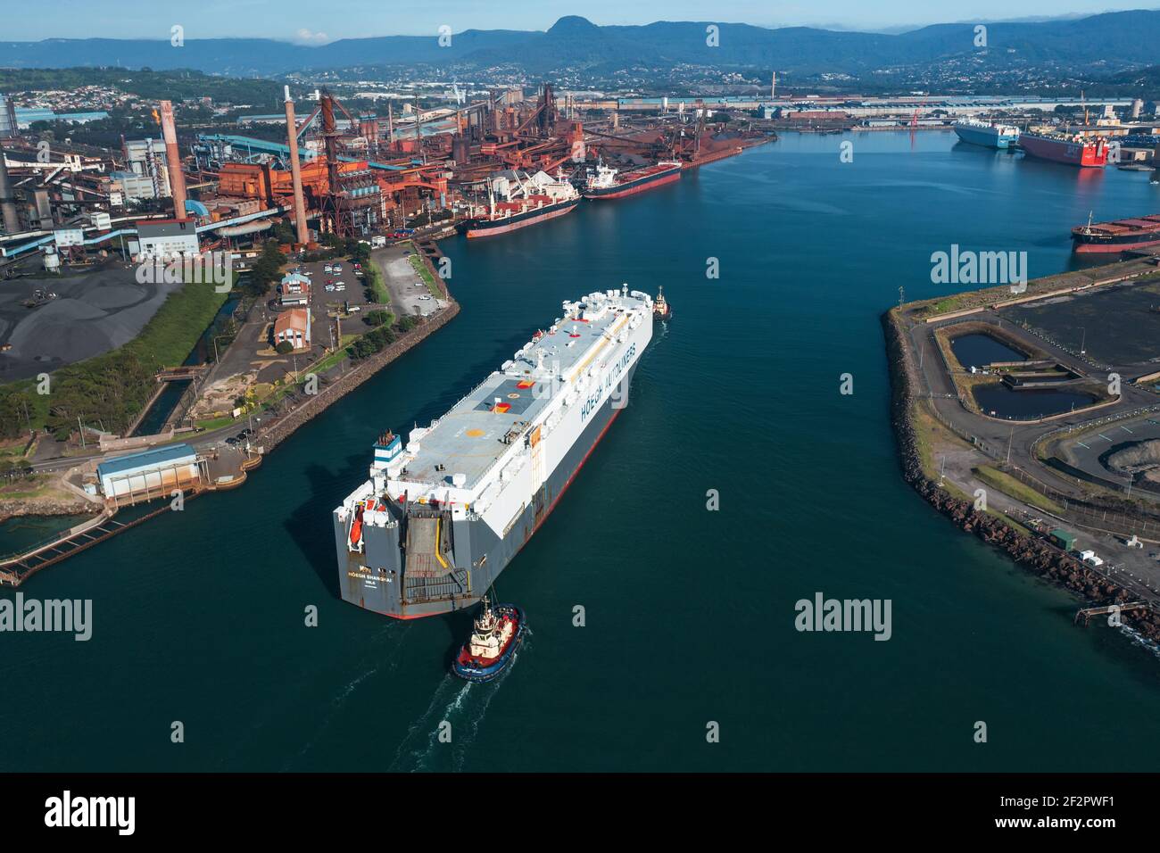 13 March 2021 - Port Kembla, NSW, Australia. Vehicles carrier HOEGH SHANGHAI enteris Port Kembla escorted by two tugboats. Stock Photo