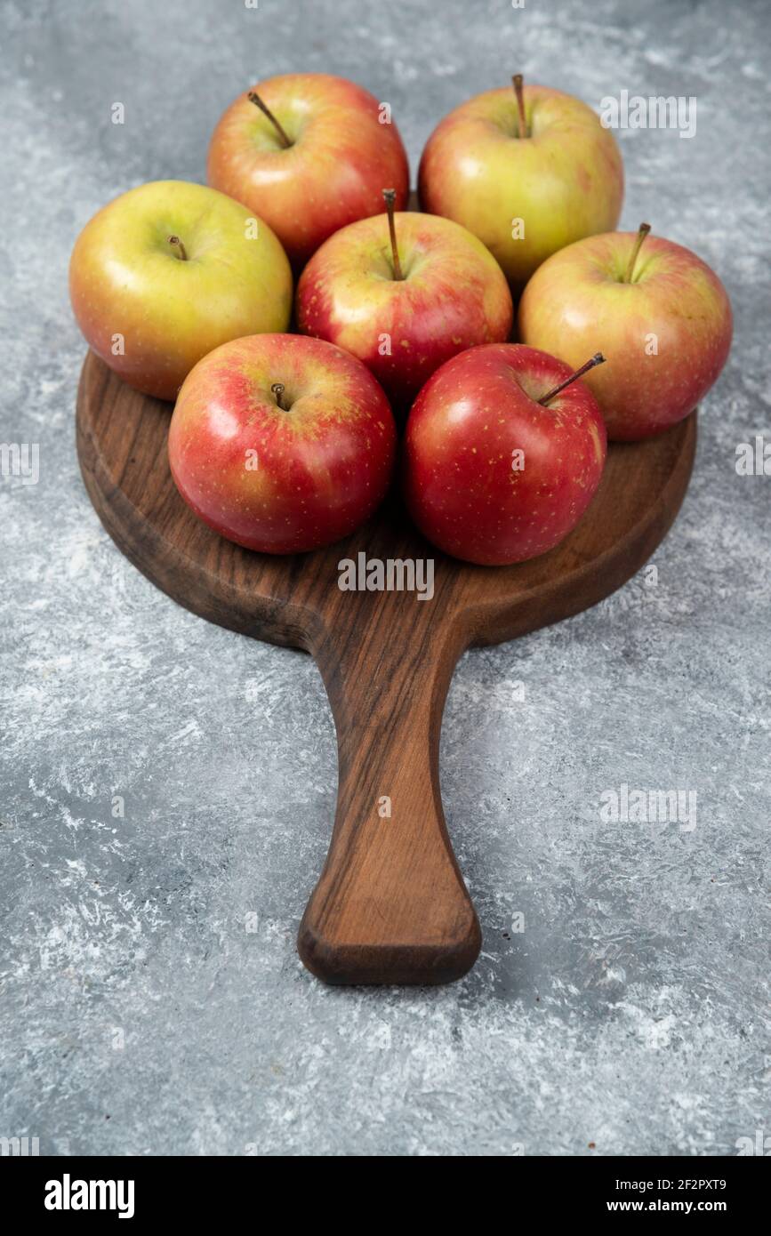 Bunch of fresh ripe apples placed on wooden board Stock Photo