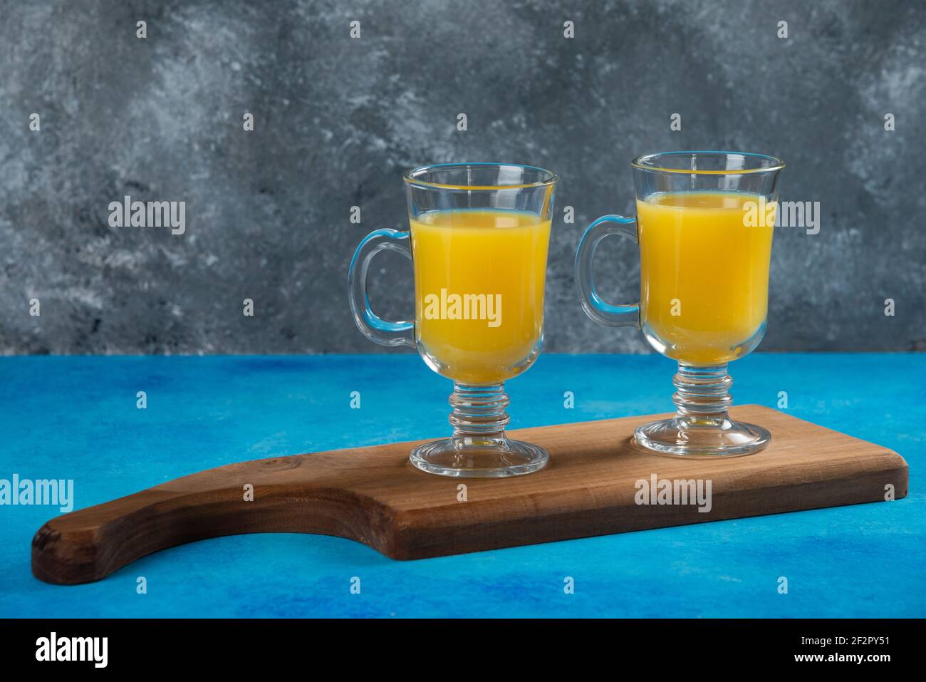Two glass cups of fresh orange juice on a wooden board Stock Photo - Alamy