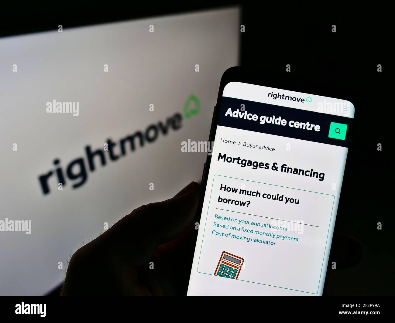 Person holding cellphone with website of British real estate online portal Rightmove plc on screen in front of logo. Focus on center of phone display. Stock Photo