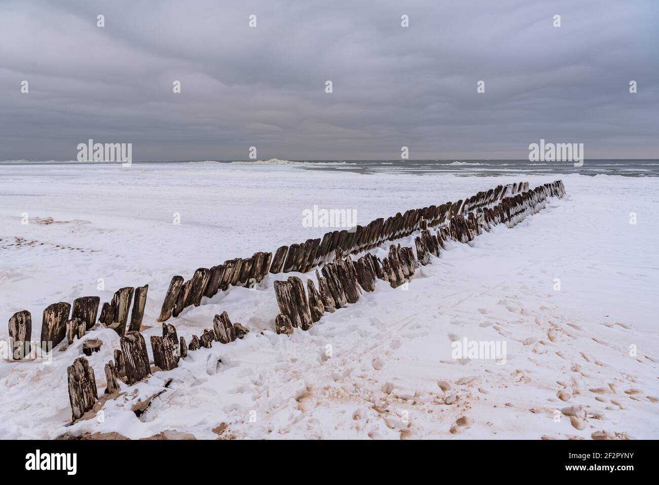 ancient boat docks with ice covered in winter and sea water washing the wooden piles is frozen Stock Photo