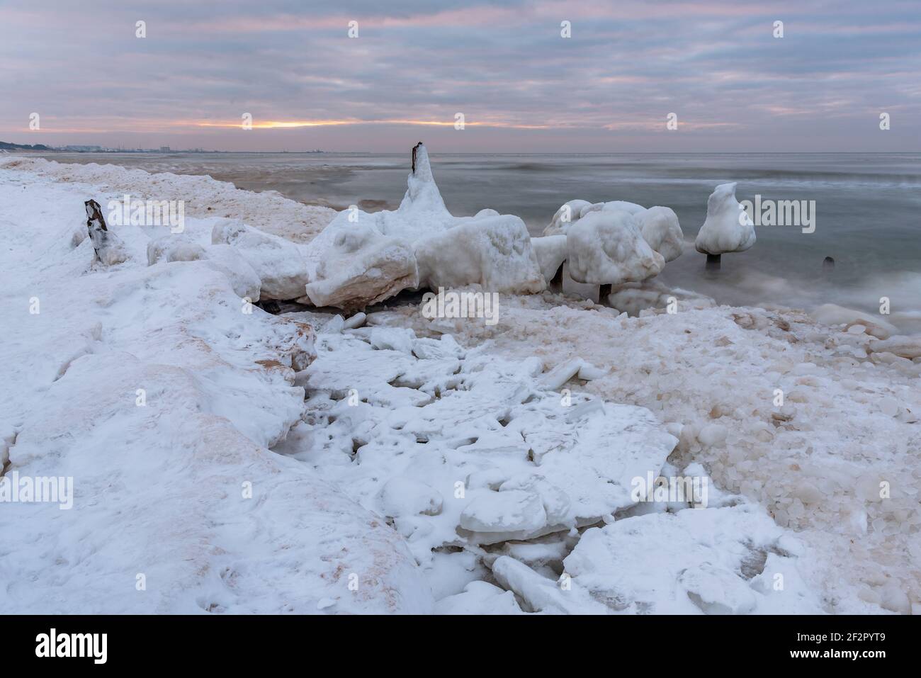 ancient boat docks with ice covered in winter and sea water washing the wooden piles is frozen Stock Photo