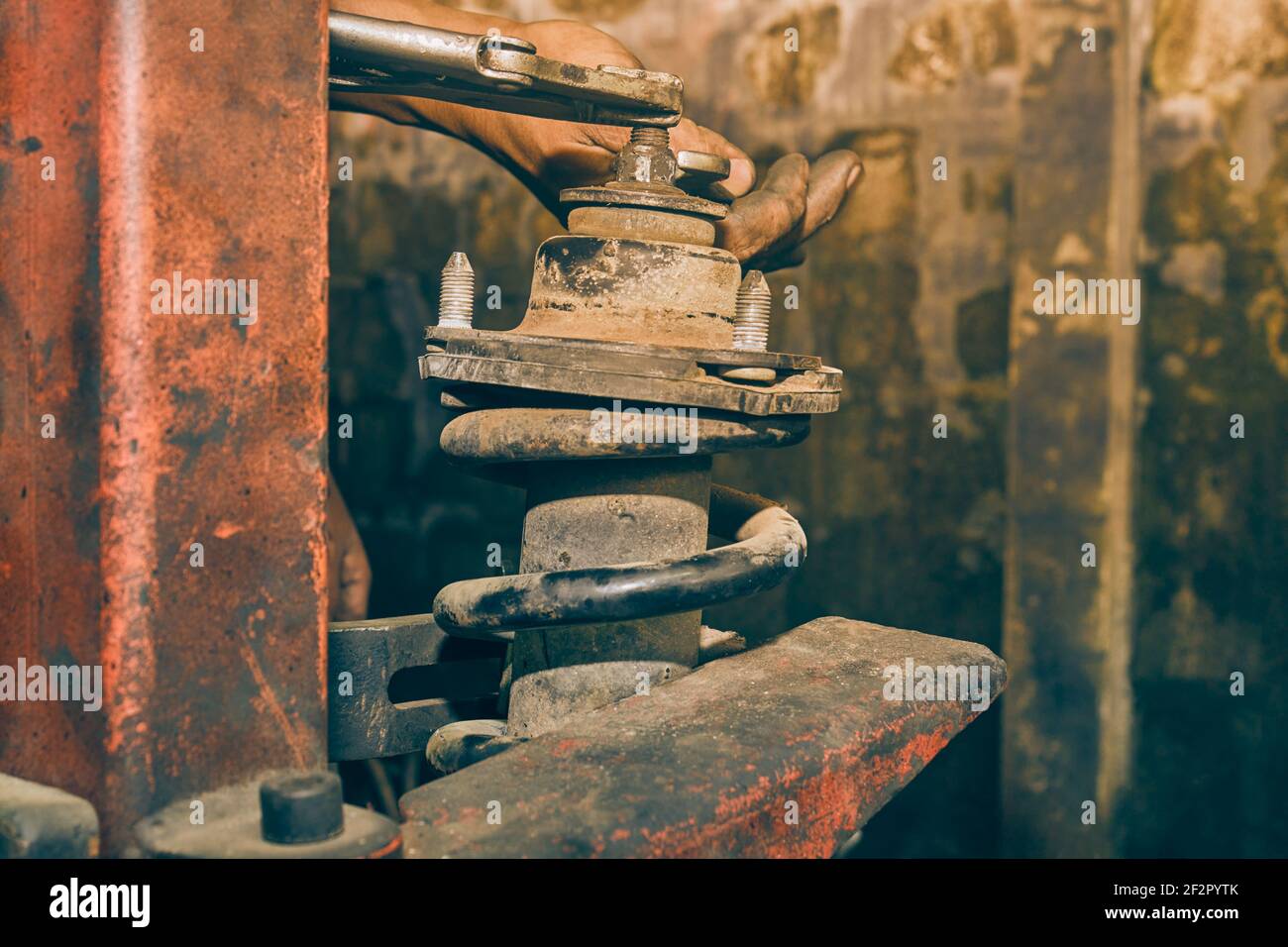 Car Mechanic or Auto Mechanic Loosen Upper Shock Absorber Nut by Wrench and Jaw Locking Pliers. Shock Absorber Removal by Spring Compressor Tool in Vi Stock Photo