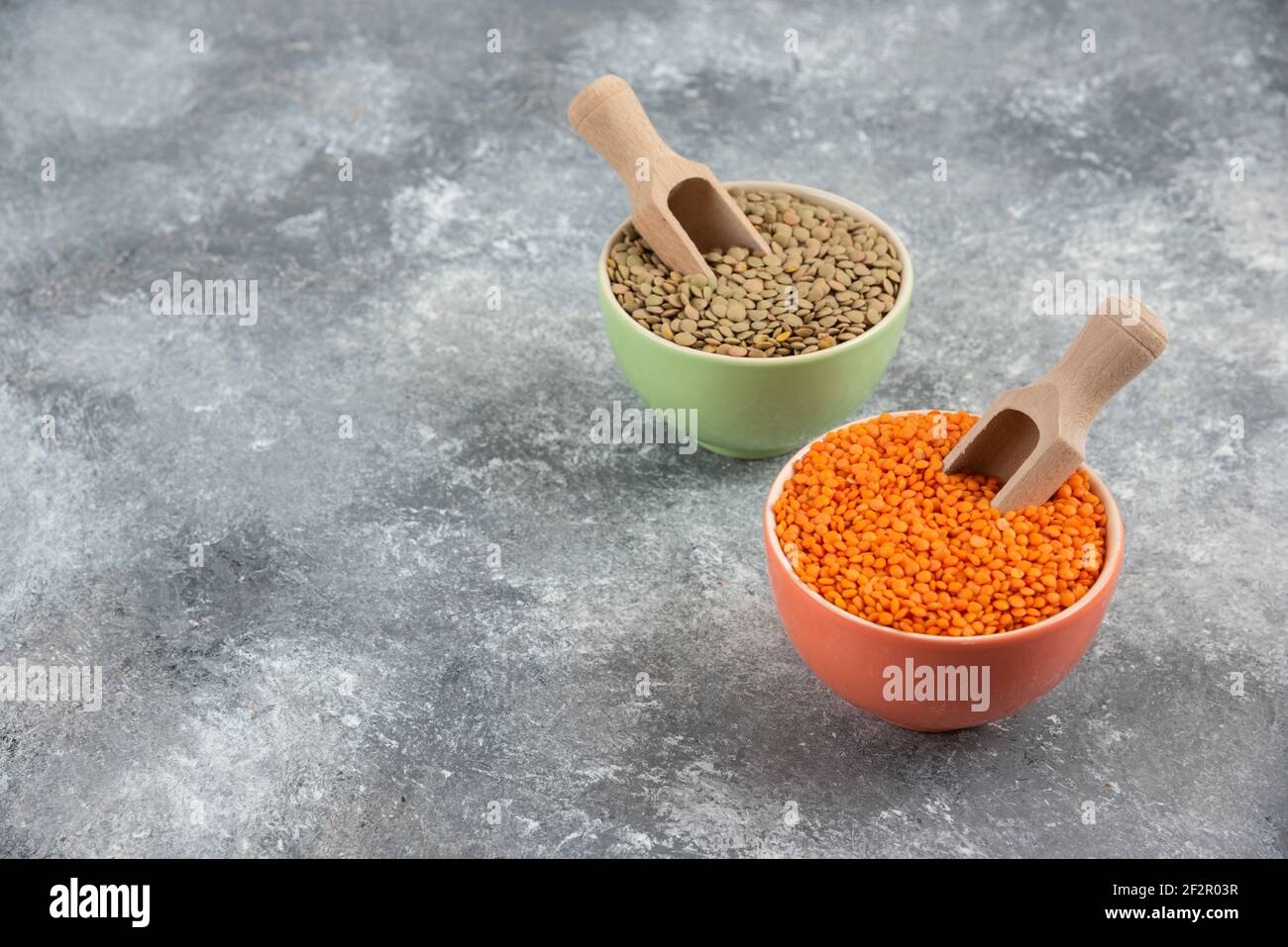 Red uncooked lentils and split peas in colorful bowls Stock Photo