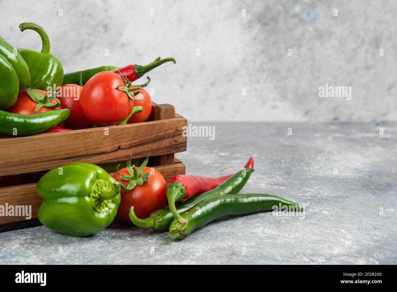 Wooden box full of fresh vegetables on marble background Stock Photo