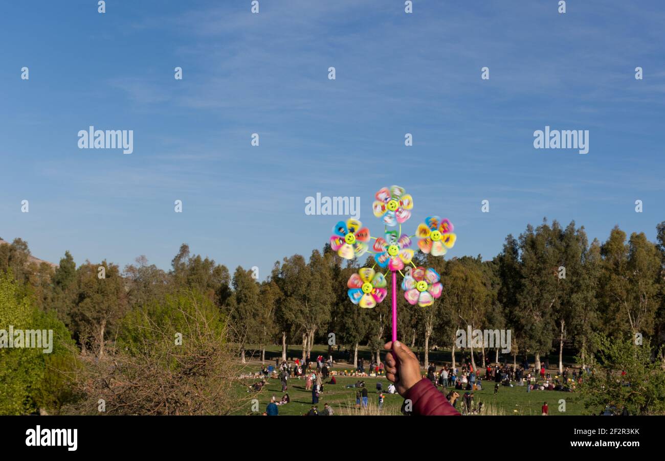 Close up man hand holding a colorful pinwheel toy with public park ...