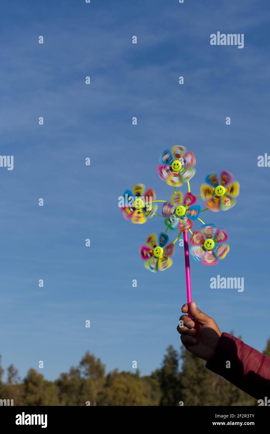 Close up man hand holding a colorful pinwheel toy with public park ...
