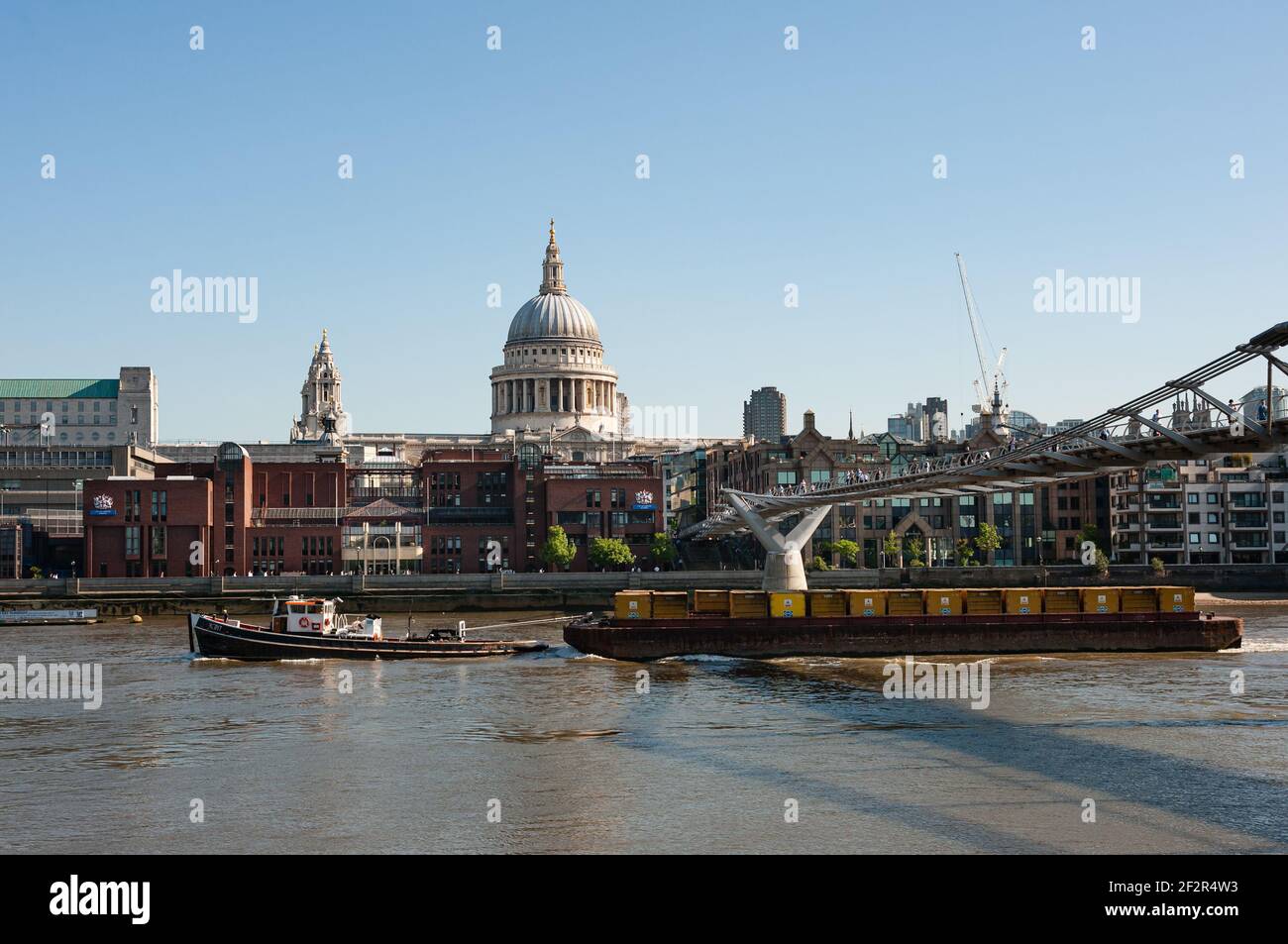 LONDON, UK - MAY 24, 2010:  Tug Towing cargo Barge under Millennium footbridge on the River Thames Stock Photo