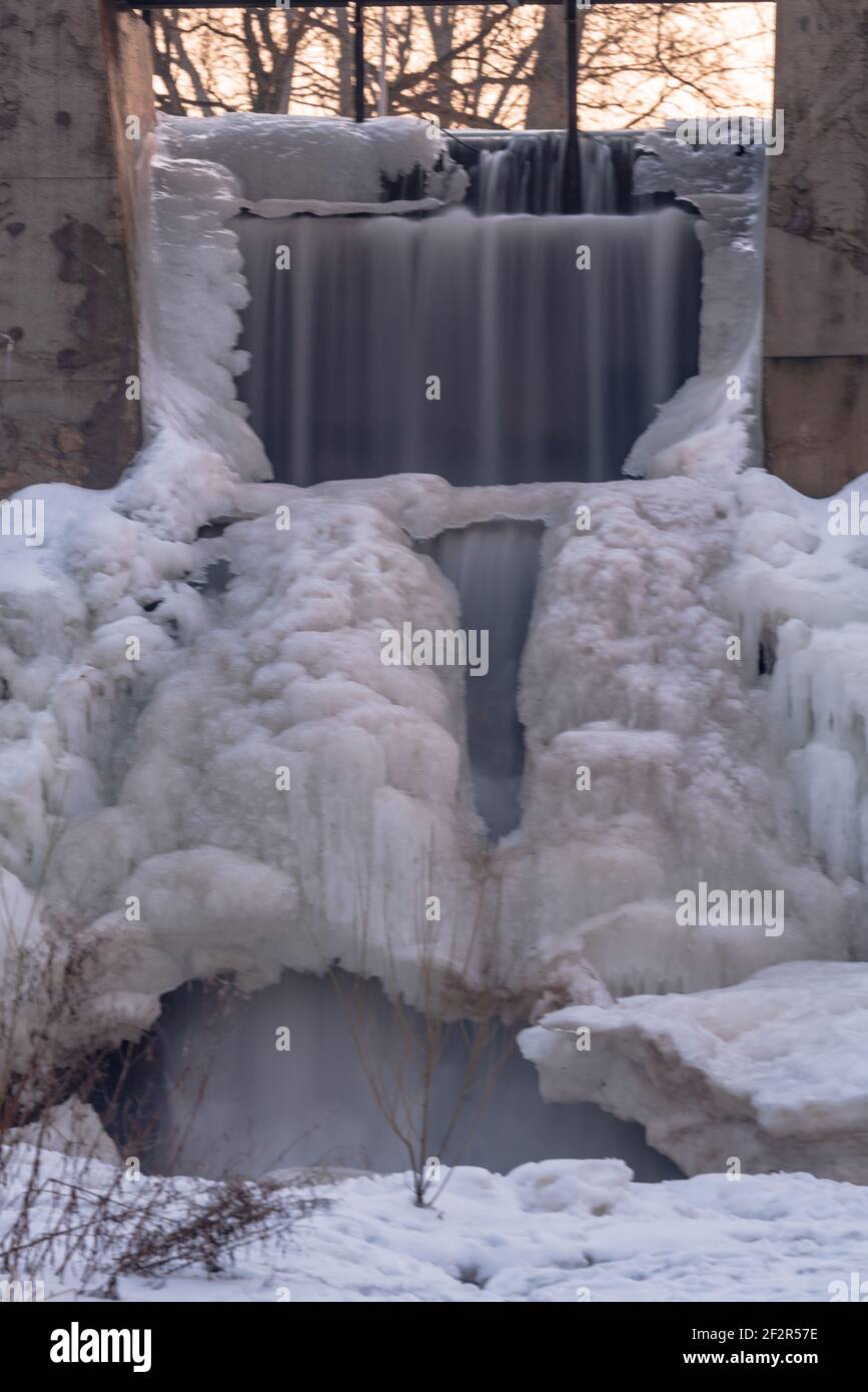 frozen waterfall near ancient watermills in an urban environment creating an impressive natural ice art work Stock Photo