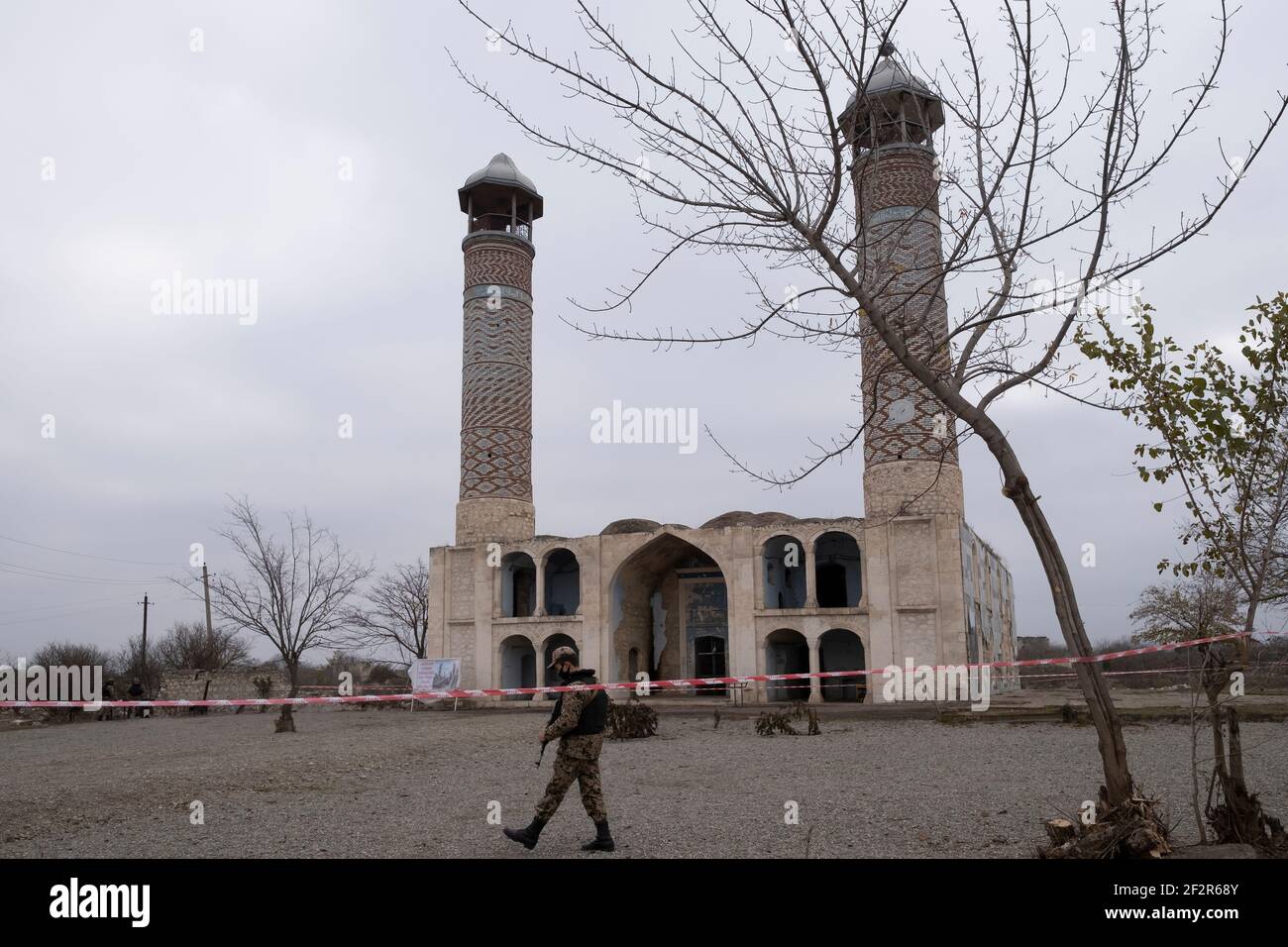 AGDAM, AZERBAIJAN - DECEMBER 14: An Azerbaijani soldier walks in front of the19th century Juma Mosque the only building left standing in the town of Agdam which was destroyed during the First Nagorno-Karabakh War by Armenian forces on December 14, 2020 in Agdam, Azerbaijan. The town and its surrounding district were returned to Azerbaijani control as part of an agreement that ended the 2020 Nagorno-Karabakh War. Stock Photo