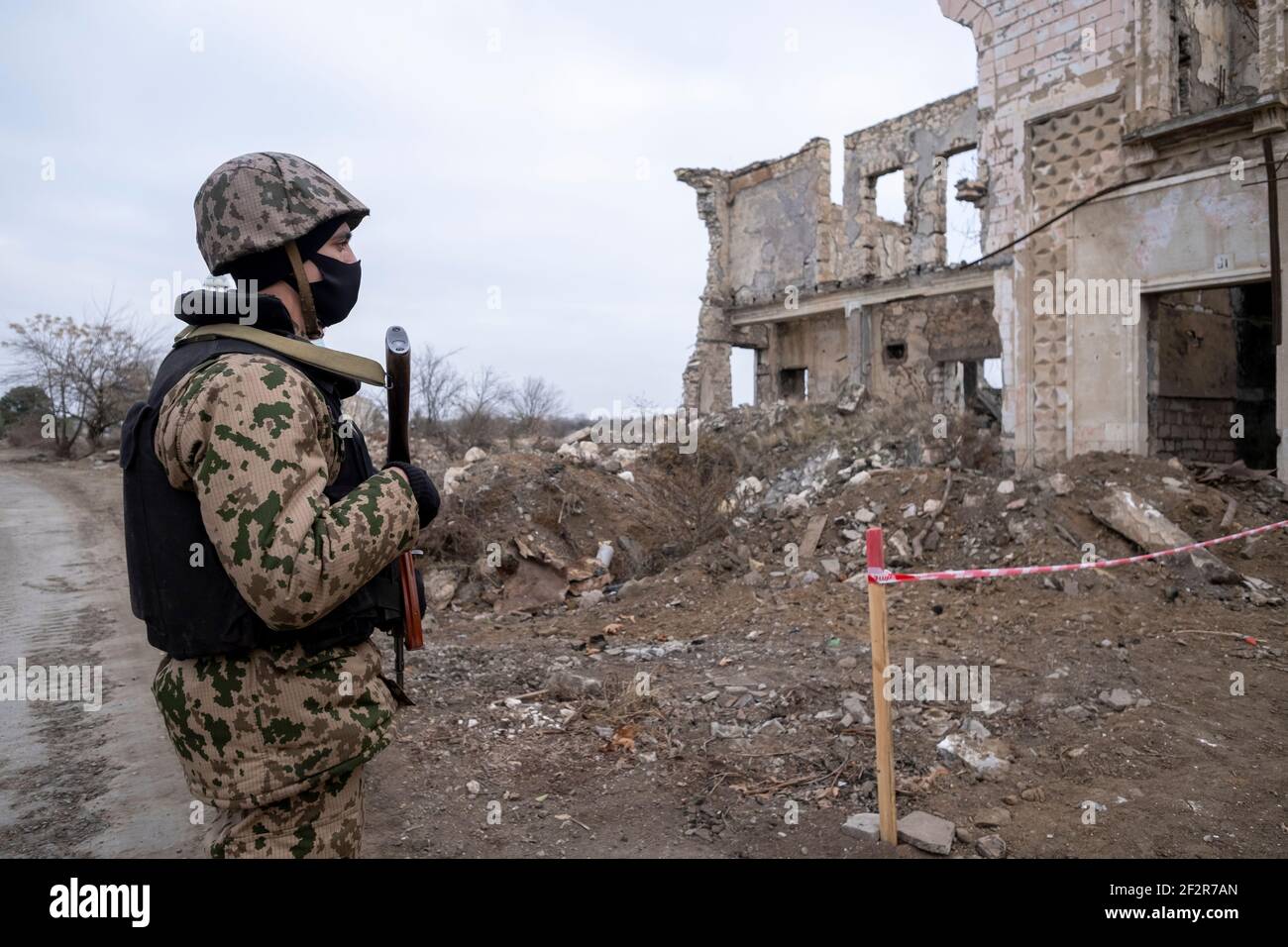 AGDAM, AZERBAIJAN - DECEMBER 14: Azerbaijani soldier looking at a ruined building in the town of Agdam which was destroyed by Armenian forces during the First Nagorno-Karabakh War on December 14, 2020 in Agdam, Azerbaijan. The town and its surrounding district were returned to Azerbaijani control as part of an agreement that ended the 2020 Nagorno-Karabakh War. Stock Photo