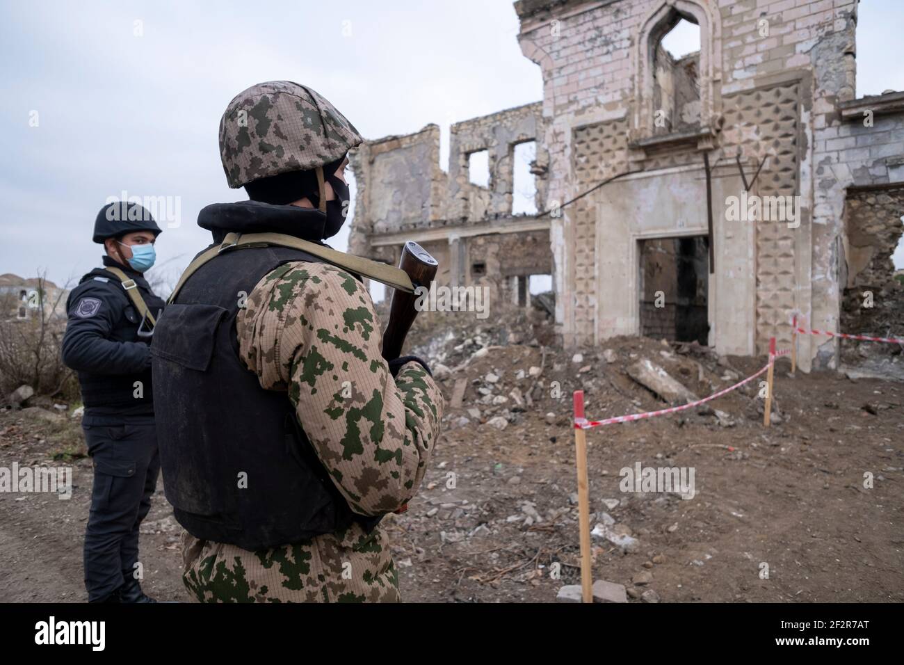 AGDAM, AZERBAIJAN - DECEMBER 14: Azerbaijani servicemen looking at a ruined building in the town of Agdam which was destroyed by Armenian forces during the First Nagorno-Karabakh War on December 14, 2020 in Agdam, Azerbaijan. The town and its surrounding district were returned to Azerbaijani control as part of an agreement that ended the 2020 Nagorno-Karabakh War. Stock Photo