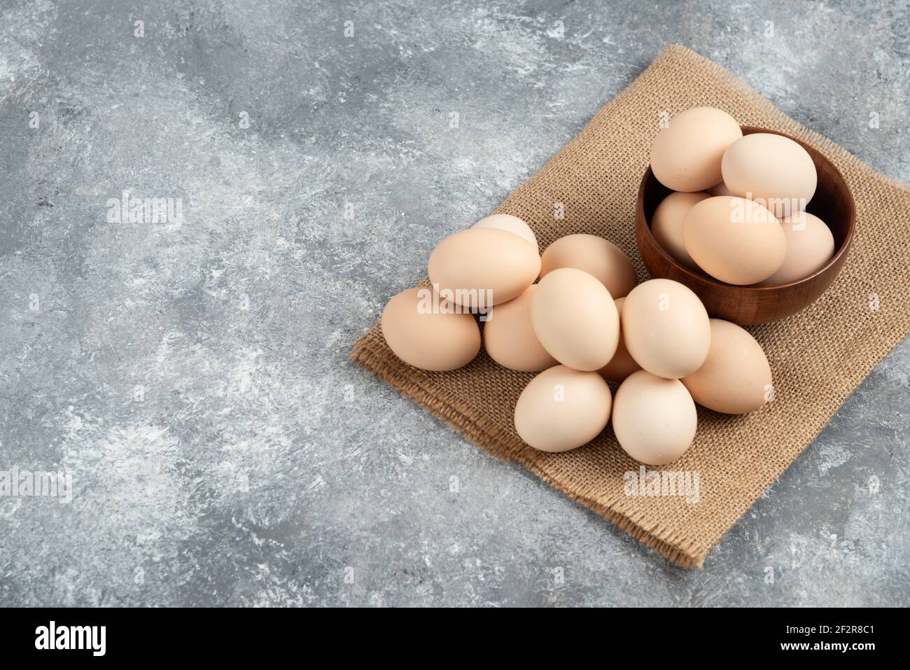 Wooden bowl of organic raw eggs on marble surface Stock Photo