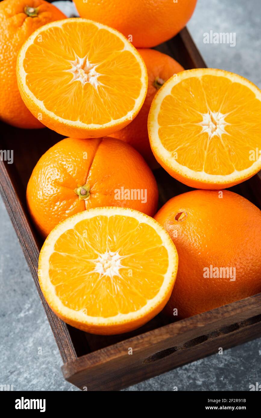 A wooden old box full of sliced and whole juicy orange fruits Stock Photo